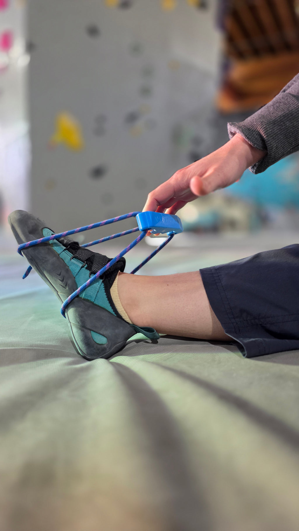 Person climbing indoors with focus on their foot wearing a climbing shoe.
