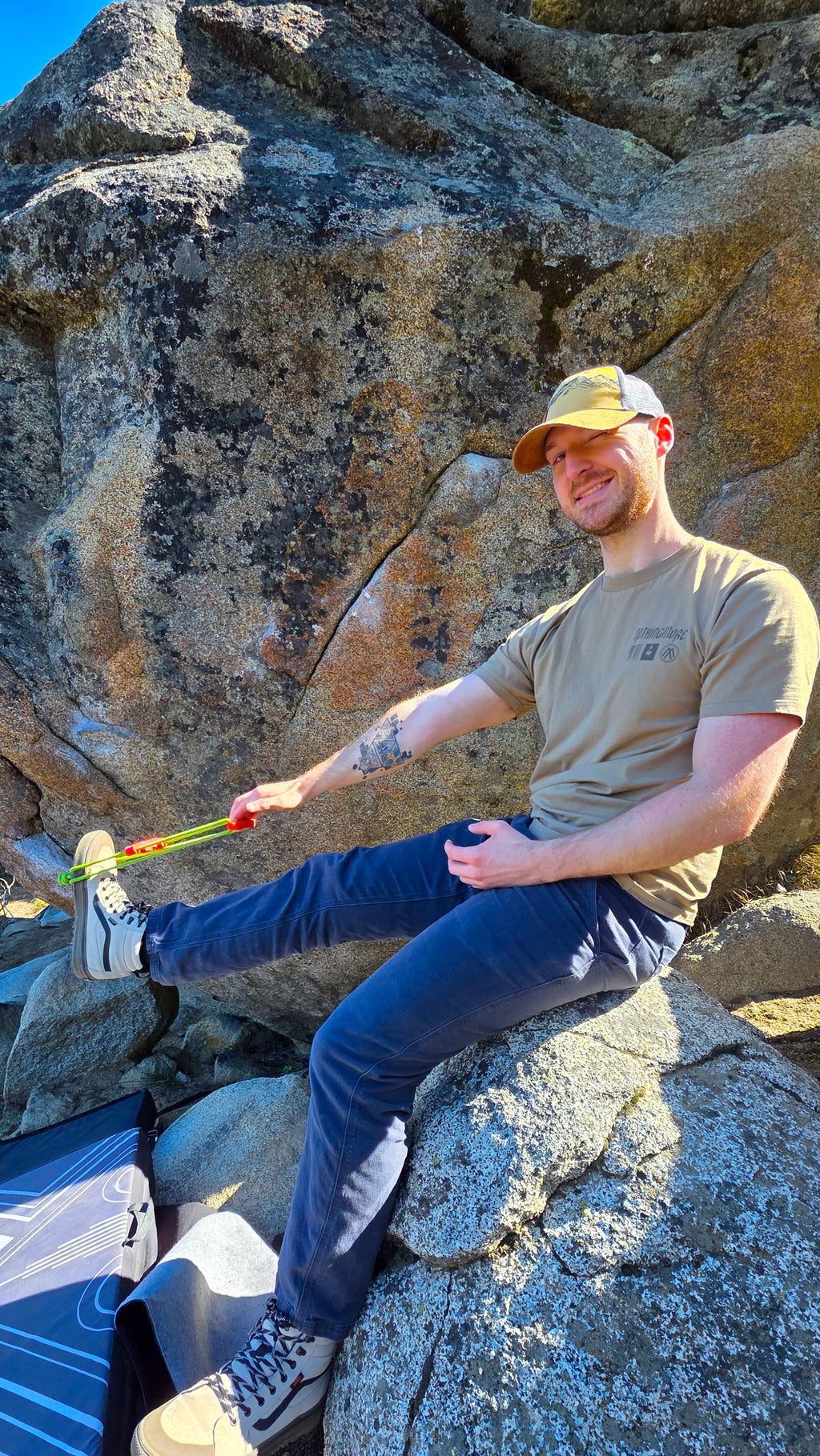 Man sitting on a rock with a minimalist, wearing a cap and casual clothing.
